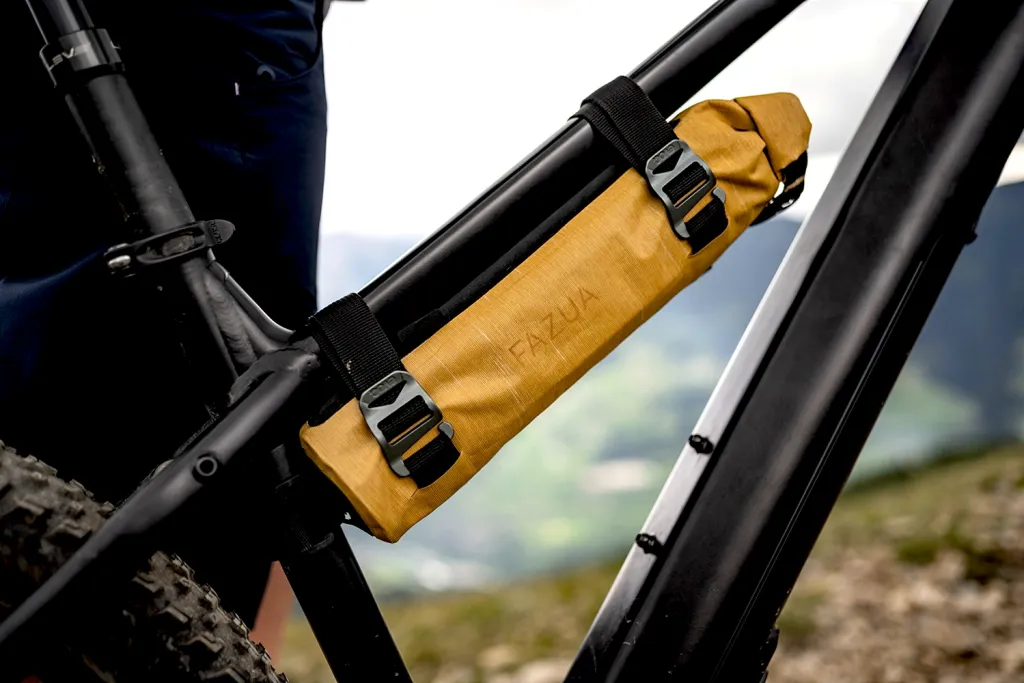 Batterie Fazua 250x dans un sac de protection, montée sur le cadre d'un vélo électrique. On aperçoit des montagnes en arrière-plan.